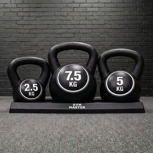 A series of GYM MASTER kettlebells of various weights on a stand, on a black brick background